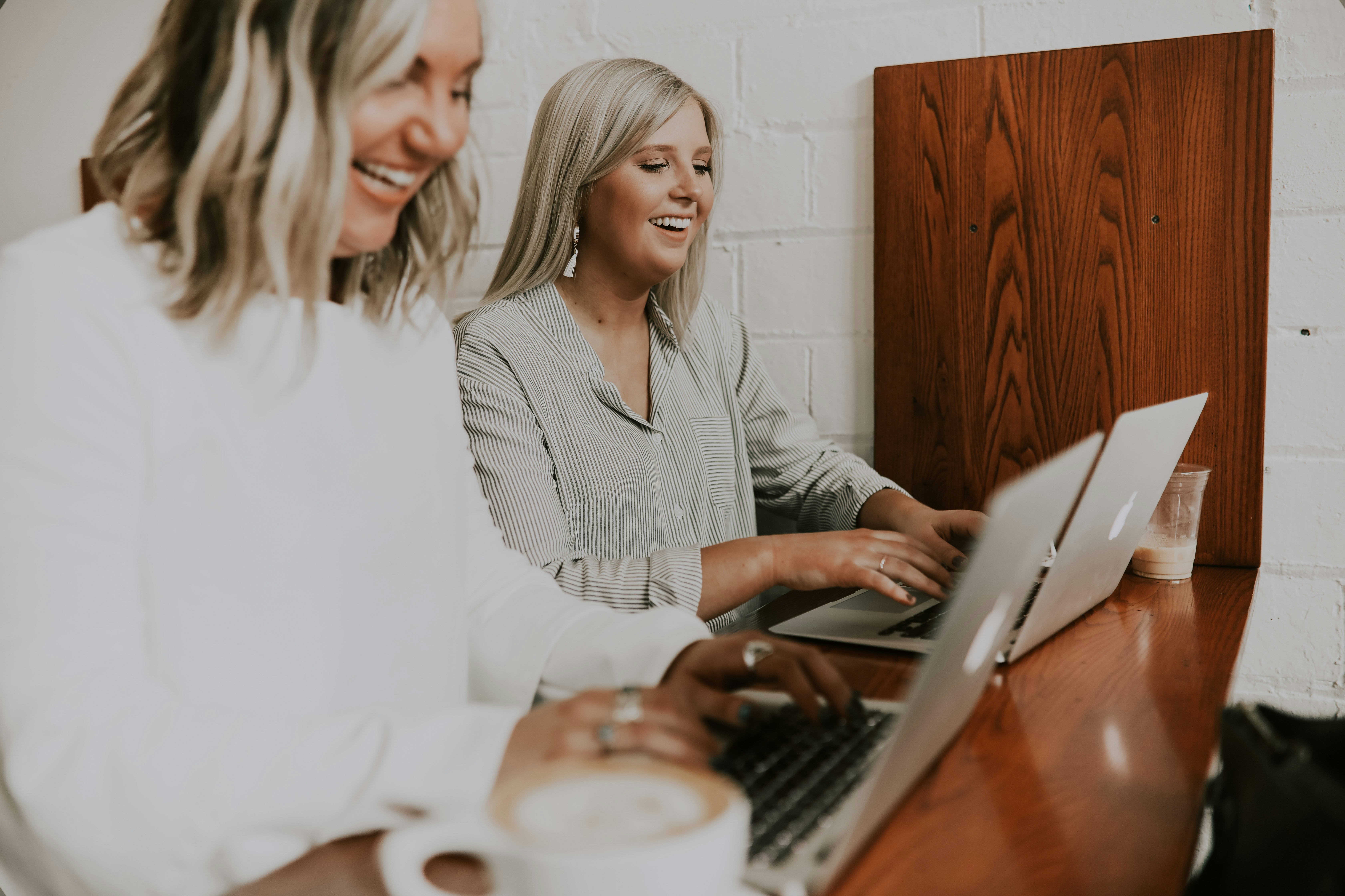 two women typing in their macbook