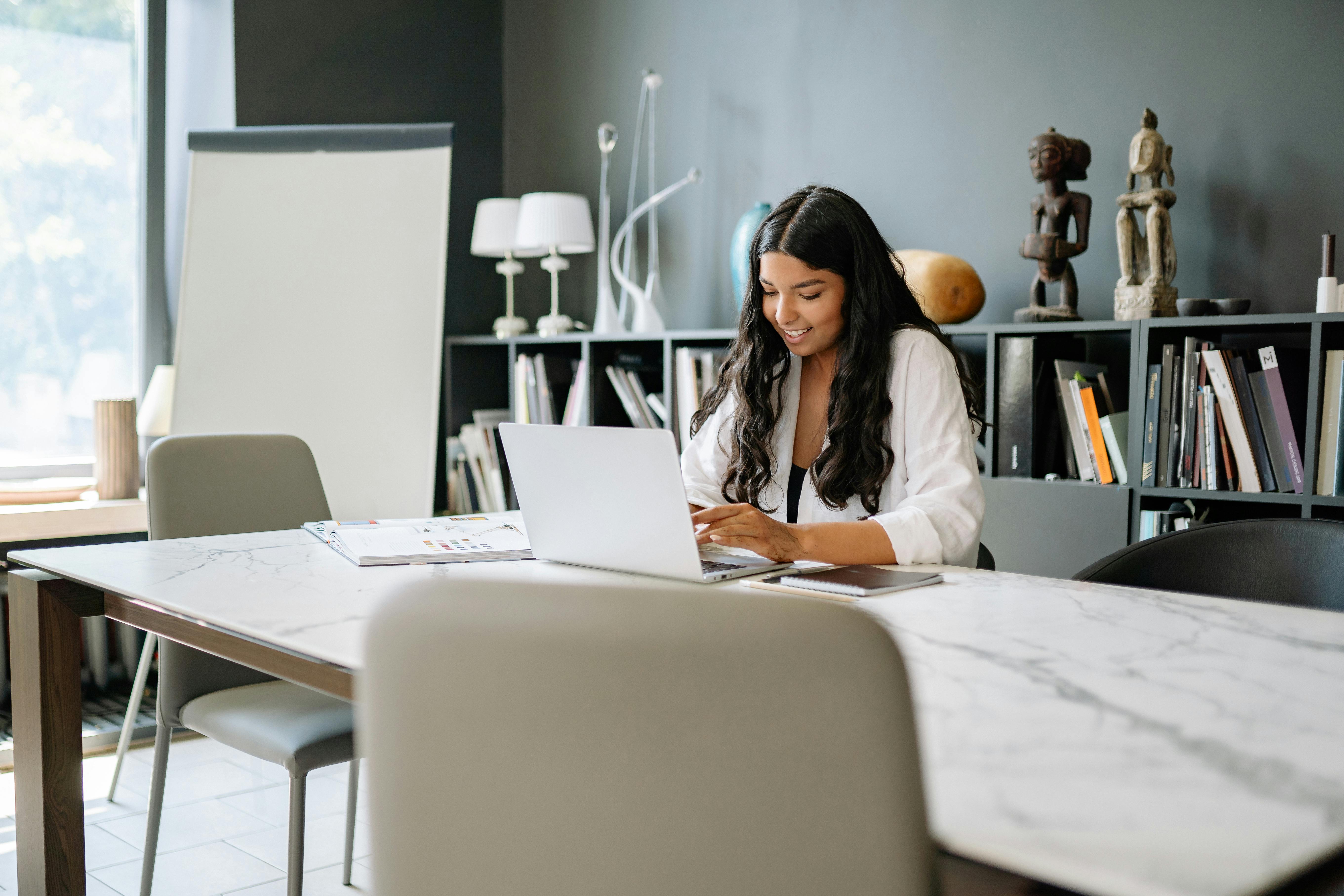 a woman sitting behind a table facing her laptop